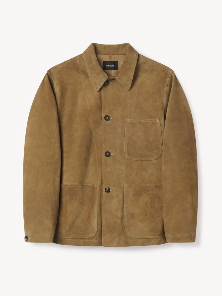Buck Mason Rambler Suede Sportsman Jacket in heath brown steerhide suede, featuring a relaxed fit chore coat silhouette inspired by the 1941 USMC utility jacket. The jacket displays three front patch pockets, a pointed collar, and dark horn-style buttons, photographed against a clean white background to highlight its craftsmanship and rich suede texture