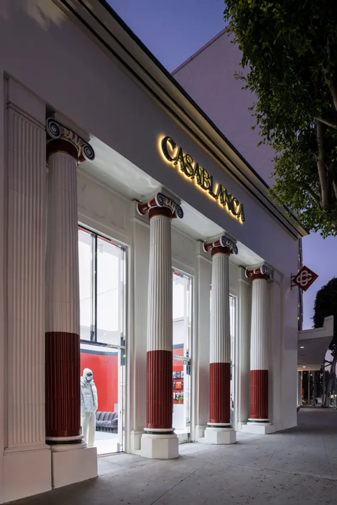 Close-up of Casablanca Beverly Hills storefront with illuminated signage and neoclassical red-and-white columns framing glass entrances, blending historic architecture with modern interior design