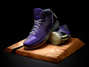 adidas D Rose 3.0 “Nightmare Before Christmas” basketball sneakers in deep iridescent purple with silver accents, displayed on a split wooden pedestal against a black background, highlighting the shoe’s reflective upper, textured midsole, and glow-ready sole design