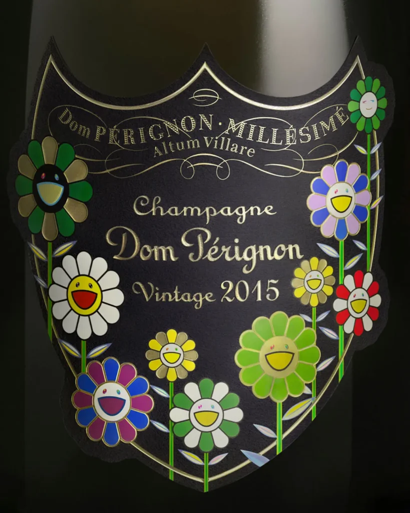 Close-up of the Dom Pérignon Vintage 2015 label from the Takashi Murakami limited edition, featuring Murakami’s signature smiling flowers in bright colors like green, yellow, red, and blue. The intricate floral artwork surrounds the classic Dom Pérignon shield, blending fine champagne tradition with Murakami’s joy and whimsical pop-art style.