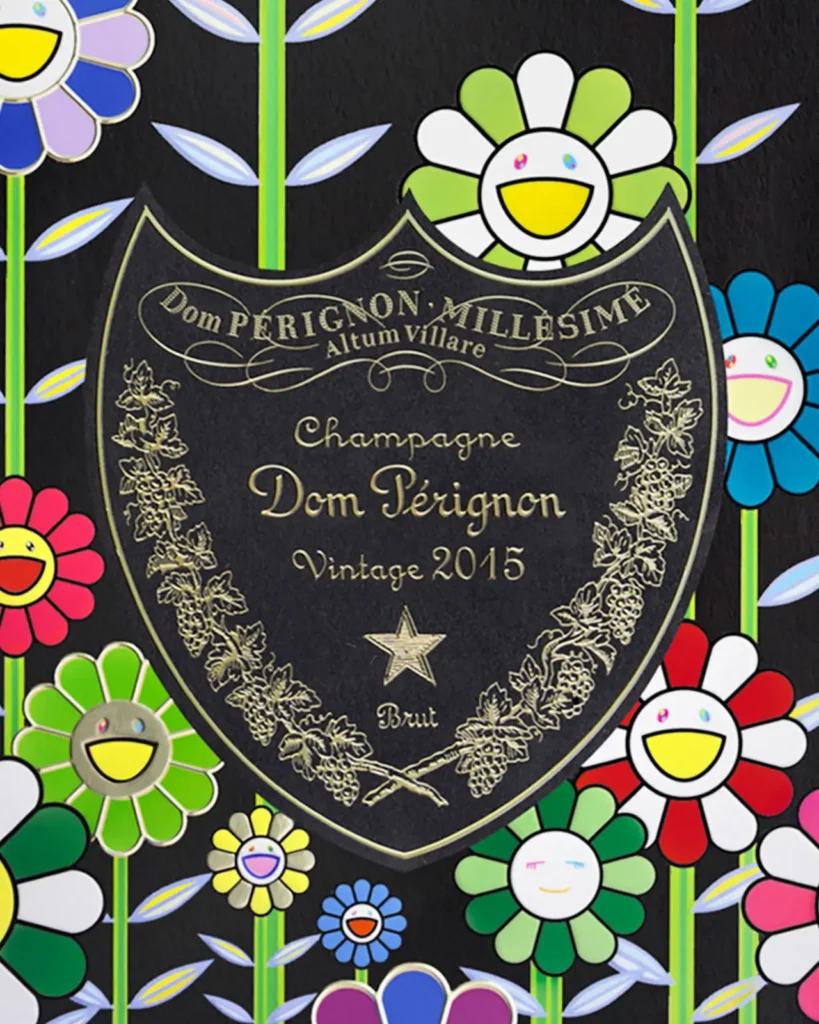 Detail view of the Dom Pérignon Vintage 2015 label from the Takashi Murakami collab, surrounded by Murakami’s vibrant smiling flower motifs in red, green, yellow, blue, and white. The iconic black and gold Dom Pérignon shield contrasts with the lively floral background, symbolizing the union of timeless champagne elegance and Murakami’s play pop-art world.