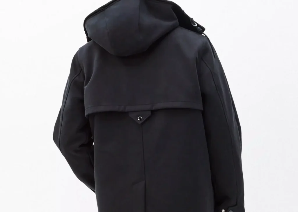 back view of the Rag & Bone Garret Coat in matte black, highlighting the hooded design, rear storm flap, and structured seam detailing for a tailored yet functional silhouette