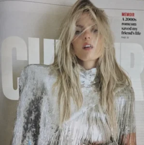 A close-up editorial portrait of a woman with tousled blonde hair wearing a high-neck, silver sequined top with long fringe detailing, posing against a neutral background from a magazine spread titled “Memoir – A 2000s romcom saved my friend’s life.”