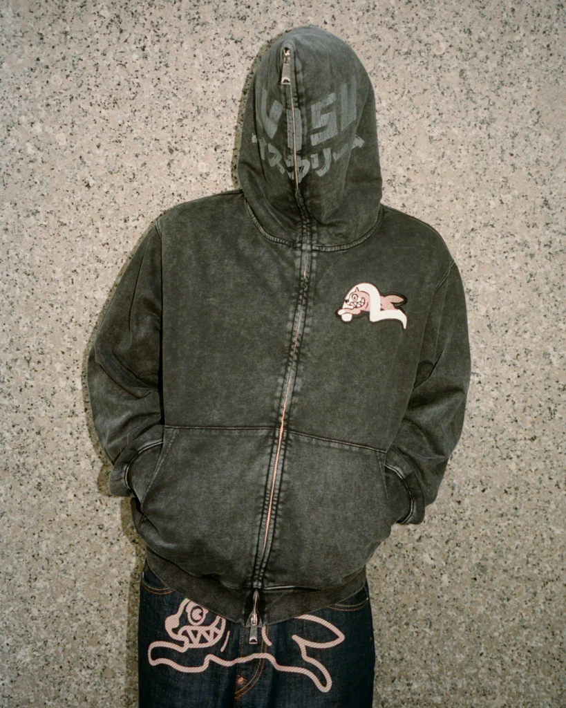 model wearing a faded black full-zip Evisu x Icecream hoodie with the Running Dog patch on the chest and matching denim jeans featuring an oversized pink Running Dog graphic on the back
