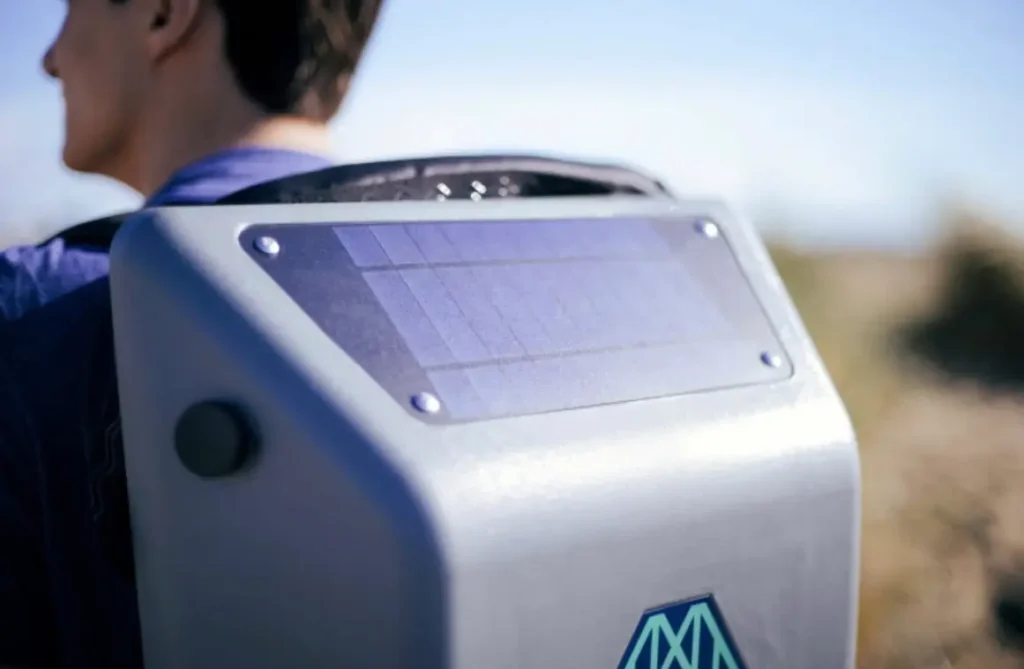 Close-up view of the HomeMore Project’s Makeshift Traveler backpack highlighting the top-mounted solar panel integrated into its grey hardshell exterior, designed to capture sunlight for charging electronic devices through its internal battery system
