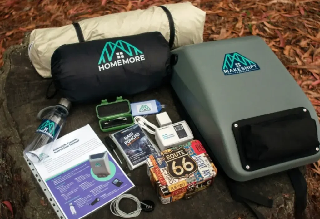 Top view of the HomeMore Project’s Makeshift Traveler kit, featuring the solar-powered backpack alongside its included items: sleeping bag, pillow, rain poncho, reusable water bottle, instruction manual, USB cables, portable charger, and safety case, all laid out on a forest surface to showcase the full set of sustainable essentials for individuals experiencing homelessness