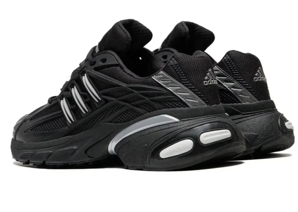 Rear and side view of the black adidas Adistar XLG 2.0 sneakers showcasing the layered mesh upper, glossy black and silver synthetic overlays, sculpted midsole with Adiprene cushioning pods, and reflective detailing on the heel