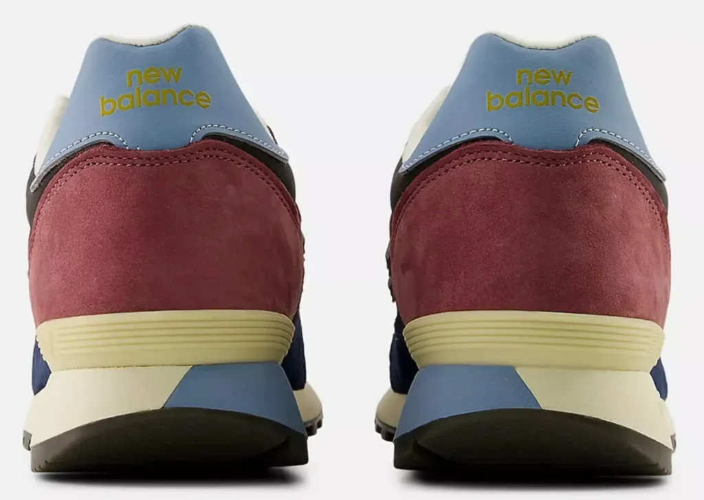 Rear view of the New Balance 475 “Washed Burgundy” sneakers showing the burgundy suede heels, light blue leather heel tabs with yellow “new balance” branding, and beige midsoles with blue heel accents