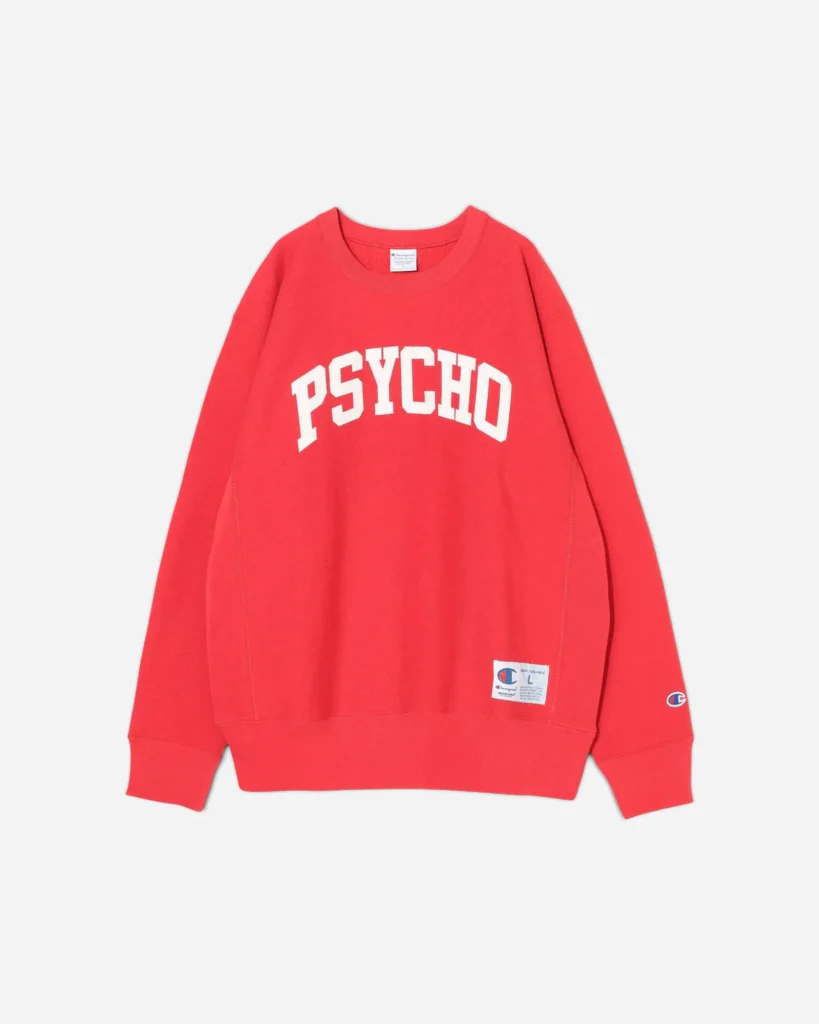 A bright red Undercover x Champion crewneck sweatshirt featuring bold white “PSYCHO” lettering across the chest, with a Champion logo patch near the hem and an embroidered “C” logo on the sleeve