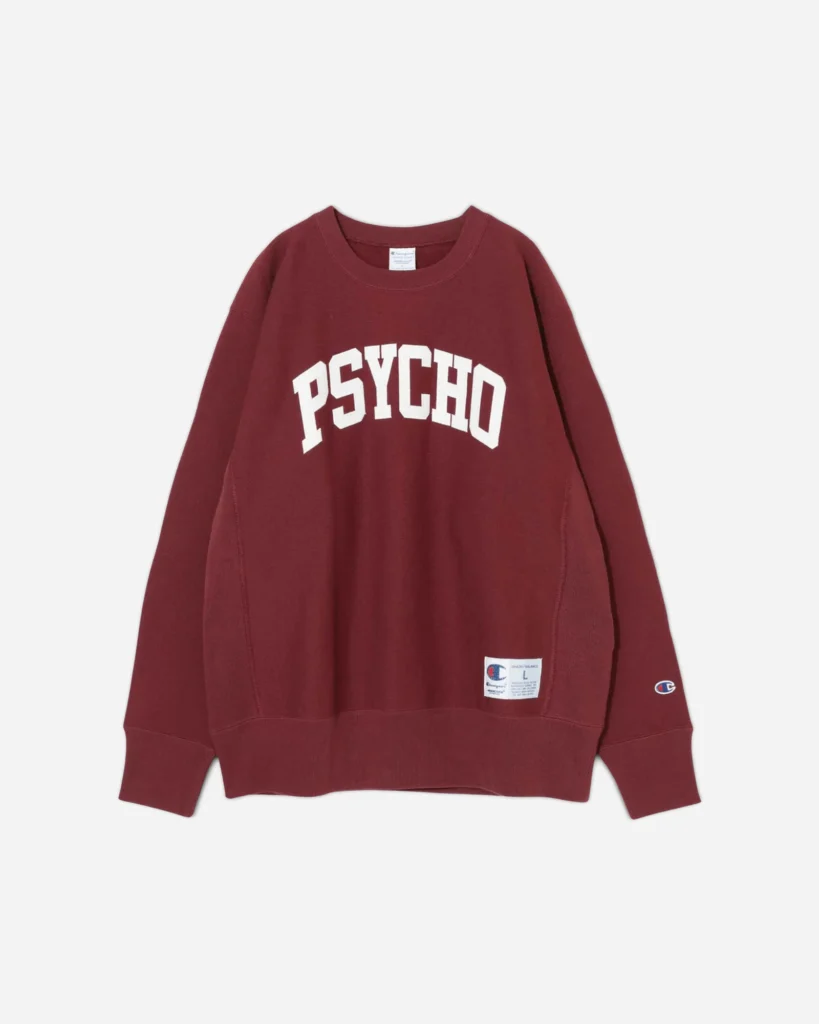 A burgundy Undercover x Champion crewneck sweatshirt featuring the bold white “PSYCHO” graphic across the chest, with Champion branding on the sleeve and a woven label near the hem