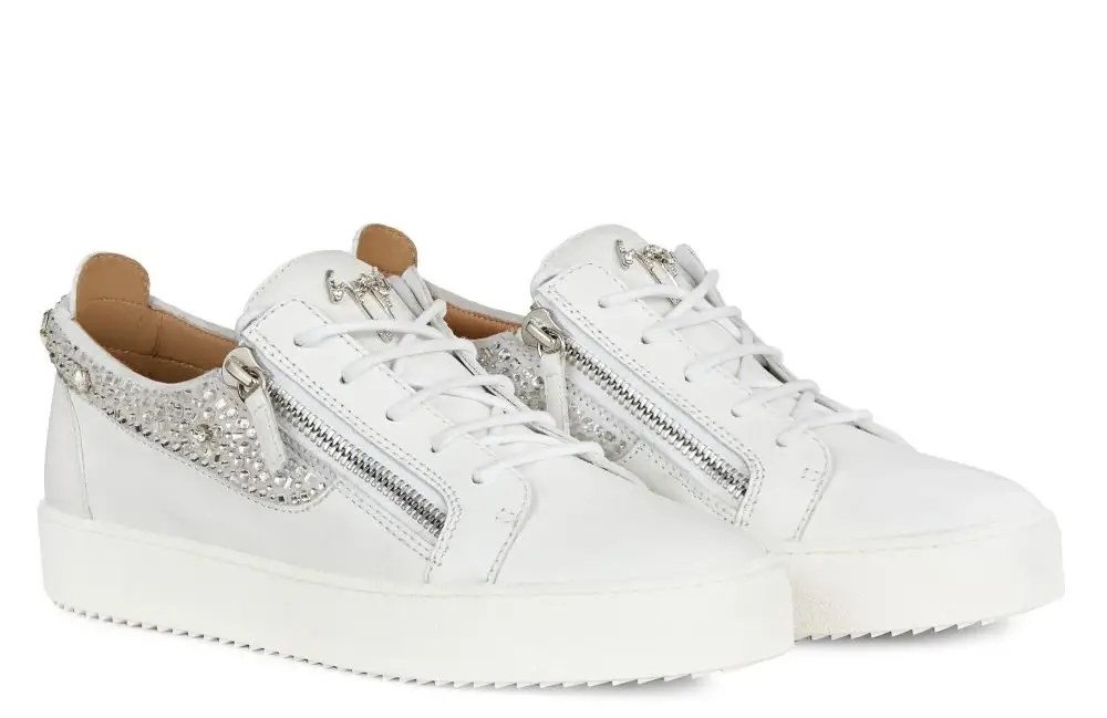 Pair of Giuseppe Zanotti white leather sneakers featuring silver side zippers, crystal-embroidered suede panels along the heel and sides, and a thick white rubber sole, photographed on a white background to highlight their texture and reflective detailing