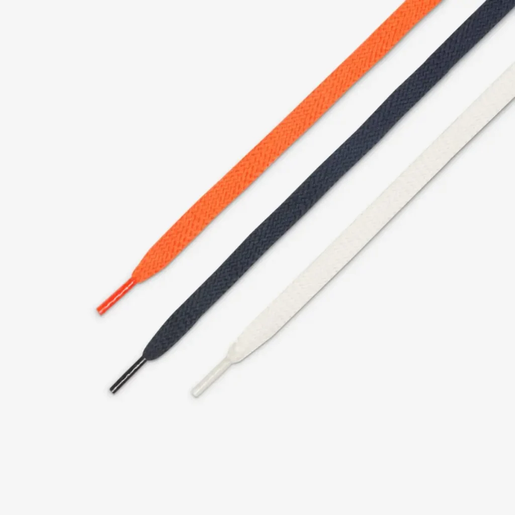 Three sneaker laces laid side by side in orange, navy blue, and white, each with matching aglets and a woven texture