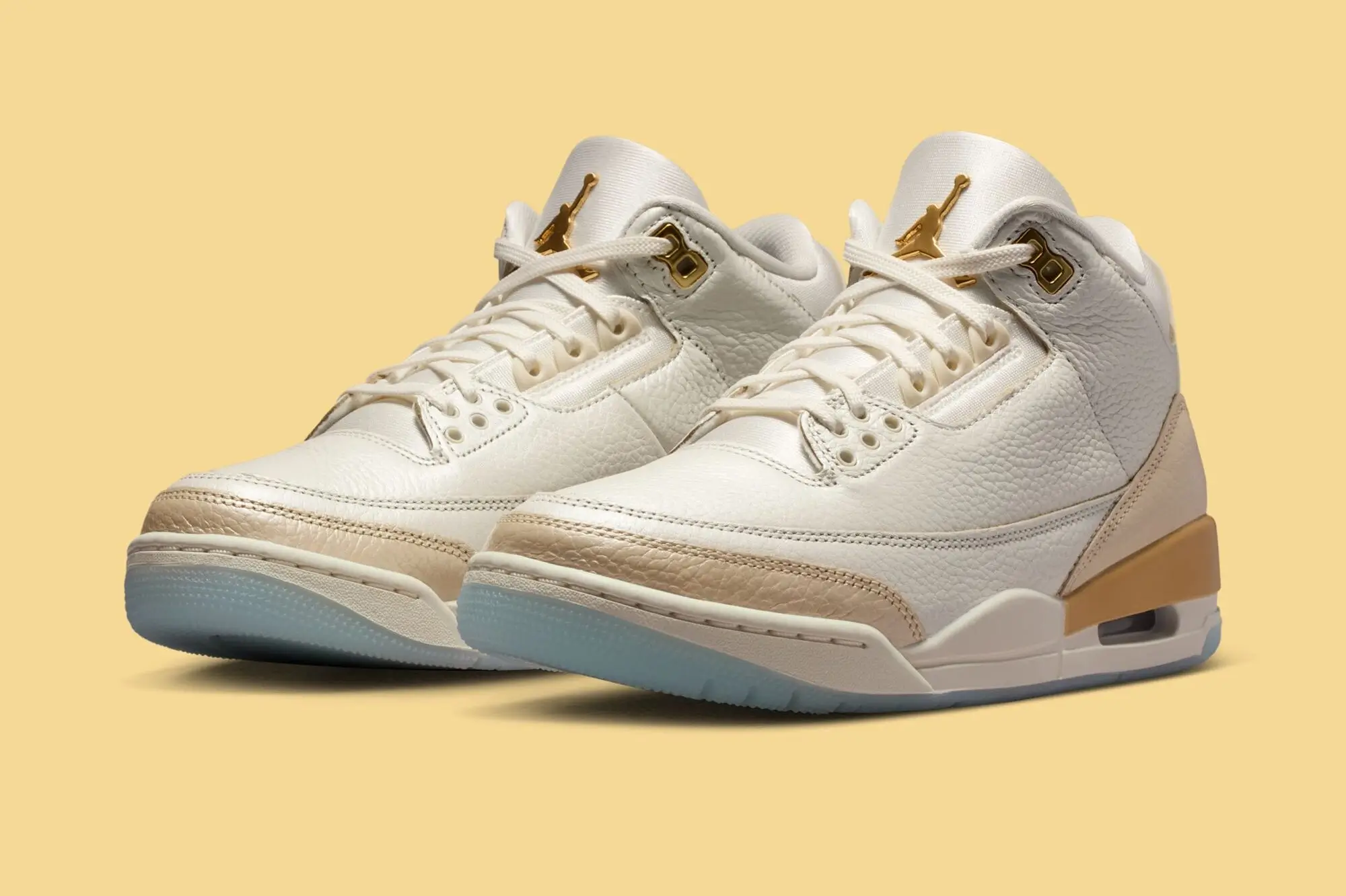 Air Jordan 3 “Champagne & Oysters” sneakers in sail tumbled leather with smooth beige overlays, metallic gold eyelets and Jumpman logos, and an icy translucent outsole, photographed against a warm cream-yellow background