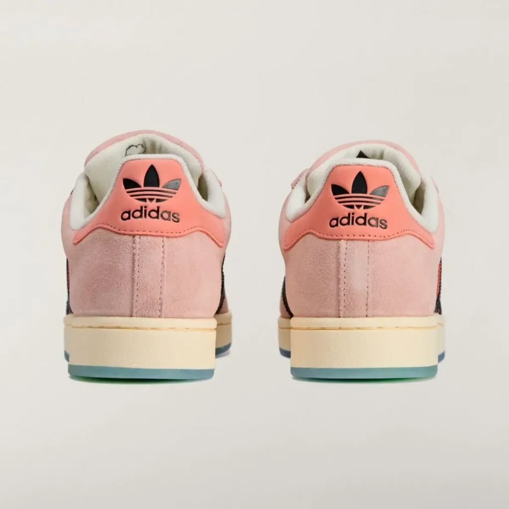 Rear view of the SpongeBob SquarePants x adidas Superstar “Patrick Star” sneakers featuring pink suede heels, coral heel tabs with black adidas Trefoil logos, and cream midsoles with blue-tinted outsole edges, photographed on a light background