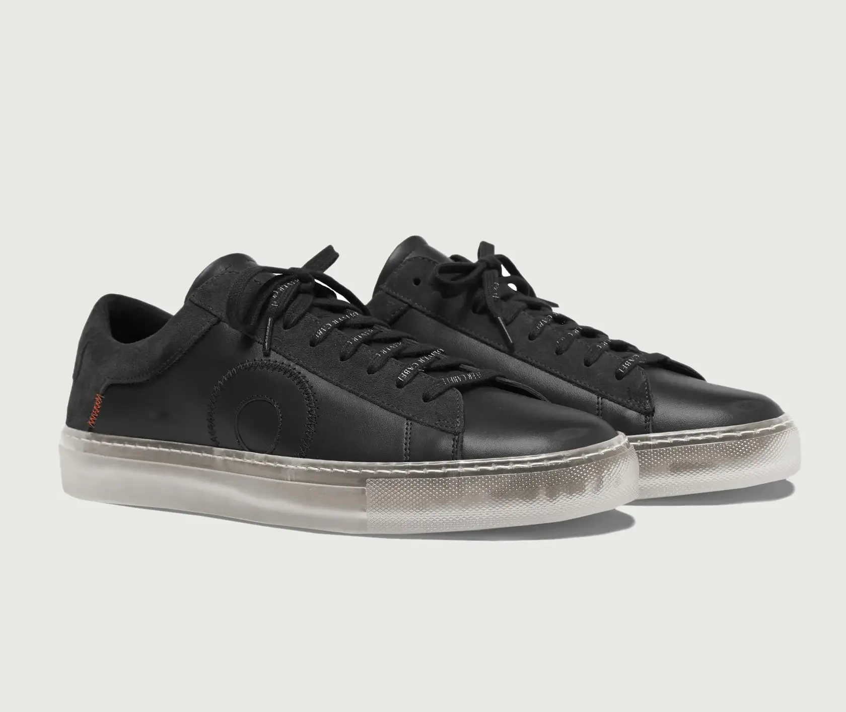 A pair of Oliver Cabell Low 1 “Black Ghost” shoes made from matte black Italian leather with tonal stitching, suede heel panels, and a translucent rubber sole, showcasing the brand’s minimalist design and orthopedic-inspired construction.