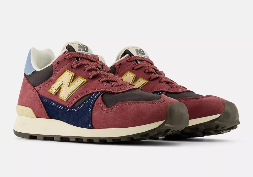 A pair of New Balance 475 “Washed Burgundy” sneakers featuring burgundy suede overlays, navy blue mid-panel accents, cream “N” logos with yellow trim, a dark mesh toebox, and a beige midsole with rugged black outsole tread