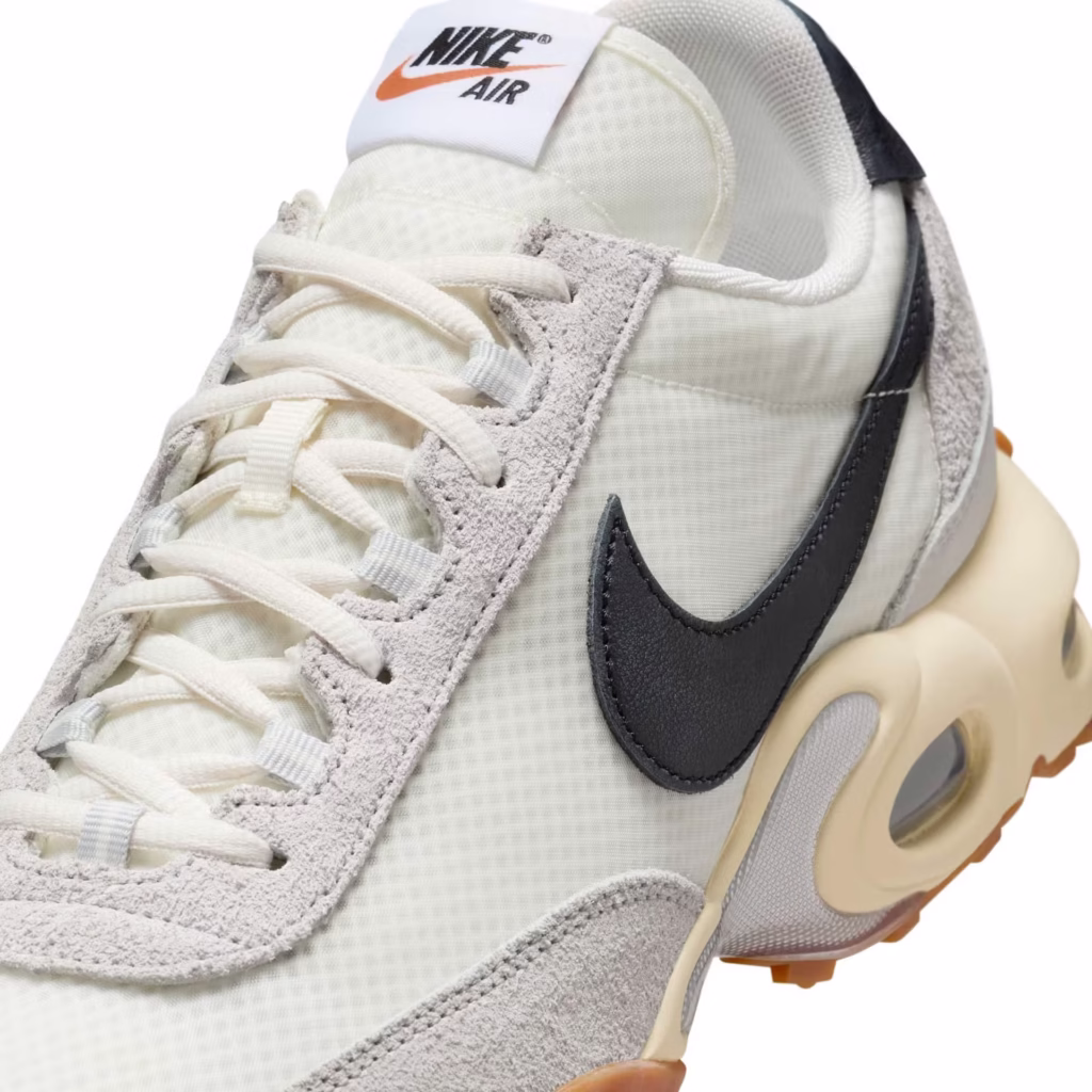 Overhead view of the Nike Air Max Waffle SP “Sail” sneakers showing the asymmetrical lacing, exposed foam tongue with woven Nike label, off-white mesh and suede textures, and sculpted midsole, photographed on a light neutral surface.