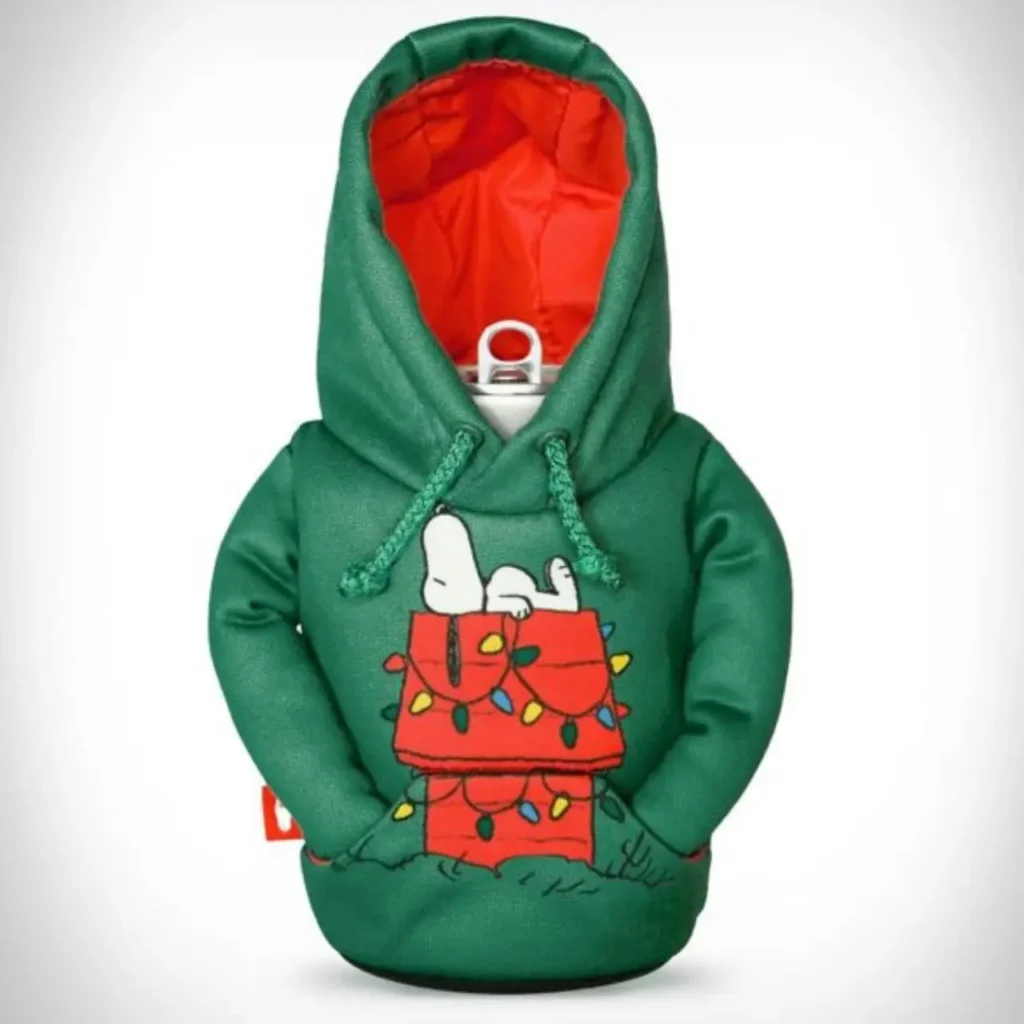 A beverage can wearing a Puffin Drinkware holder styled like a green holiday hoodie featuring Snoopy lying atop his Christmas-light-covered red doghouse, with a bright orange hood lining and green drawstrings for a festive seasonal look