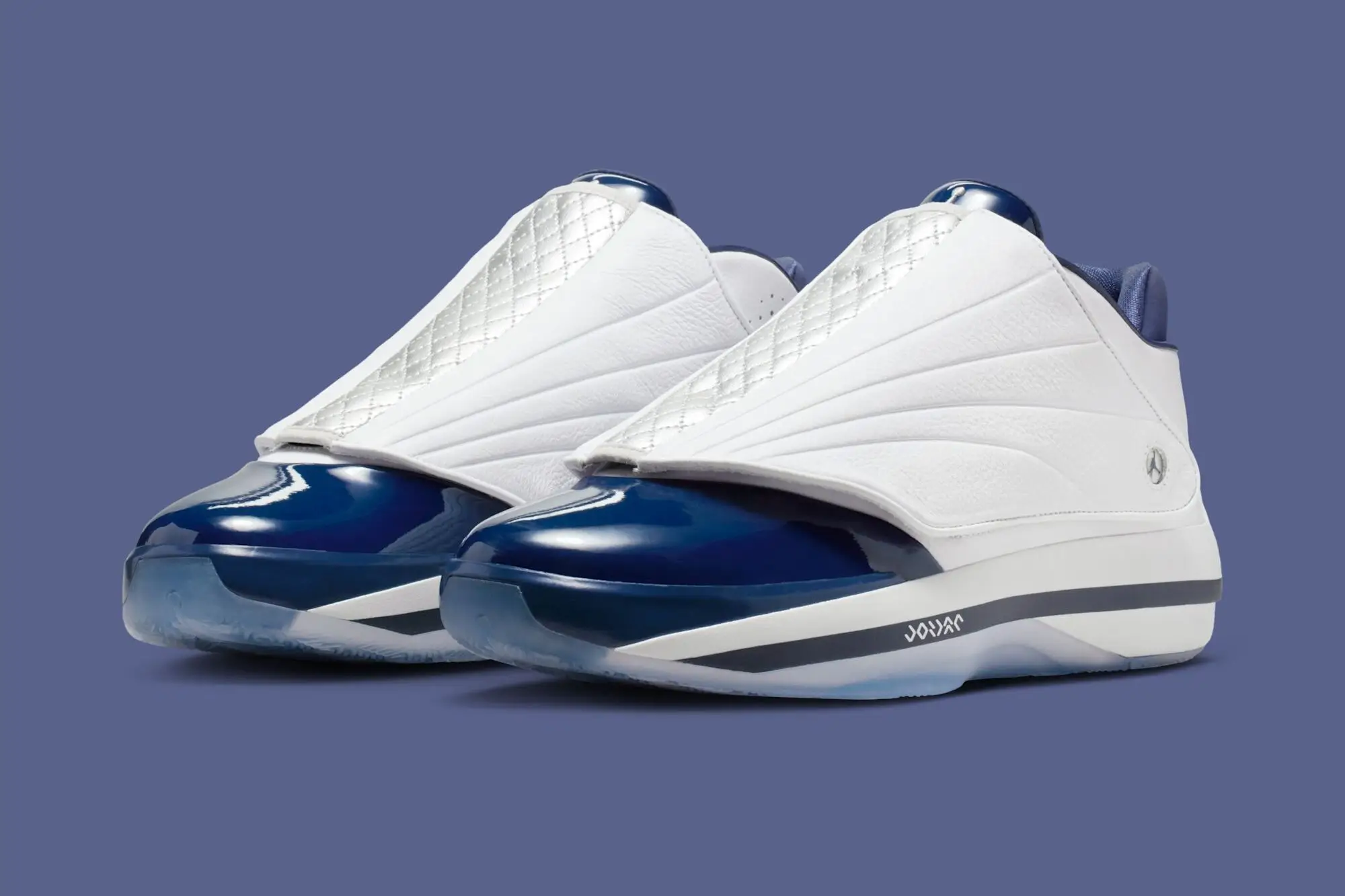 Air Jordan 4016 “Midnight Navy” sneakers shown in a three-quarter rear view, featuring a white leather upper with a quilted shroud, glossy midnight navy patent leather mudguard, navy inner lining, and a white midsole with dark accent branding, set against a muted blue background