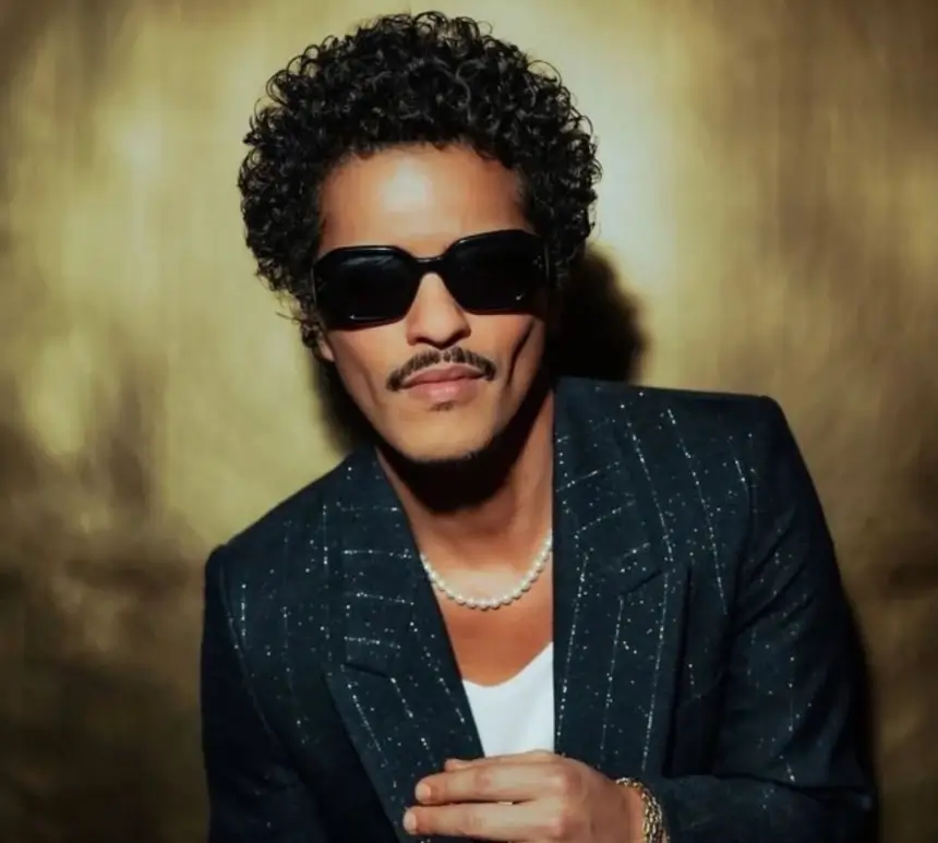 Portrait of Bruno Mars in black sunglasses, pearl necklace, and tailored jacket