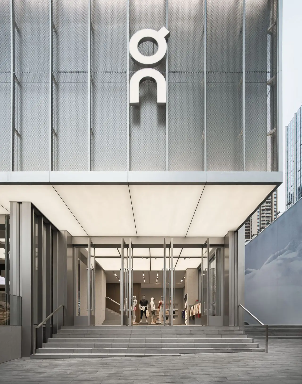Exterior entrance of the On Running flagship store at MixC World featuring the illuminated On logo above a modern glass storefront and steps leading into the two-floor retail space
