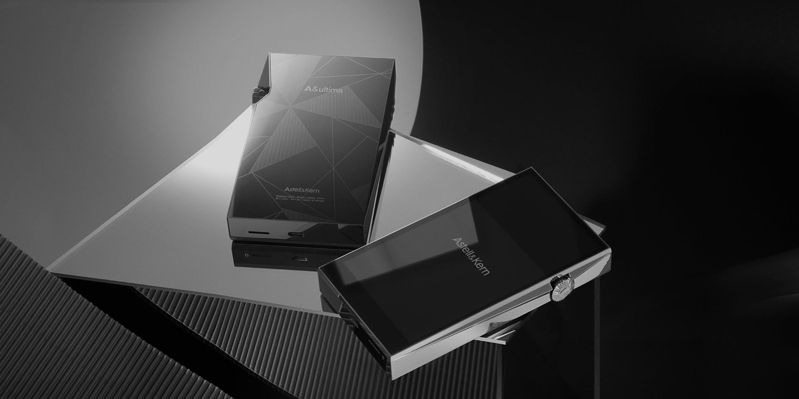 Astell&Kern PD20 luxury portable audio players displayed on geometric metallic surfaces, featuring angular brushed metal design, touchscreen interface, and signature side volume wheel in a high-end studio setting