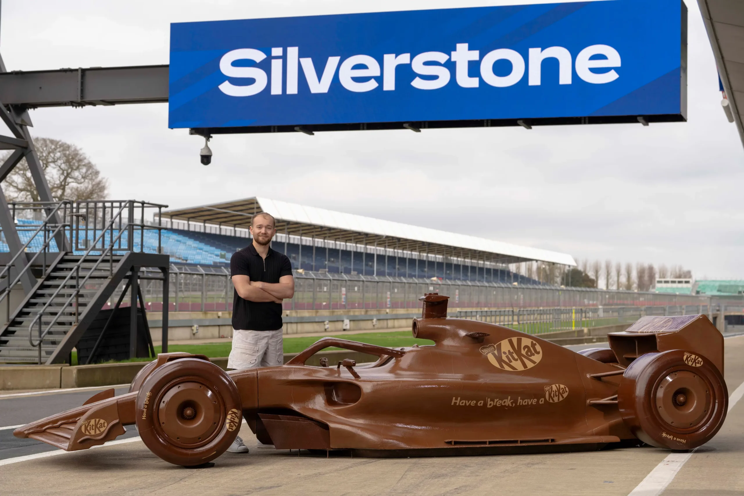 Life-sized Formula 1 race car sculpture made entirely of chocolate with KitKat branding and the slogan “Have a break, have a KitKat,” displayed indoors as part of a promotional campaign connected to Formula One