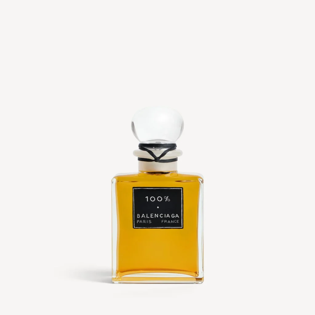 Front view of Balenciaga 100% perfume bottle with amber liquid, square glass design, black label reading “100% Balenciaga Paris France,” and a rounded glass stopper wrapped with a black cord