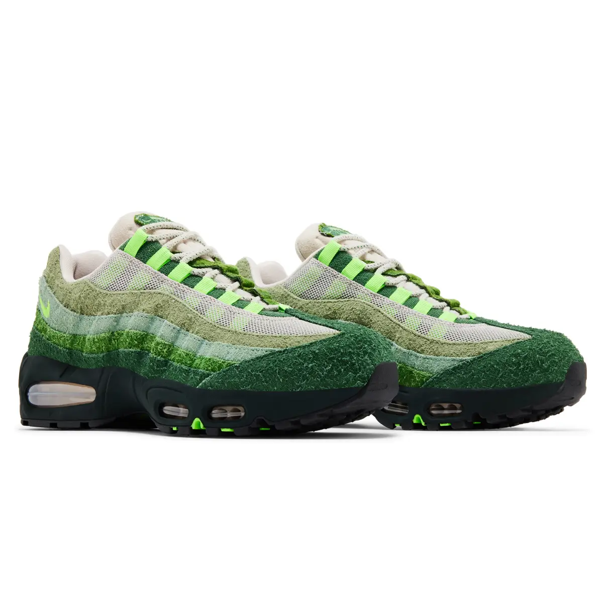 Pair of Nike Air Max 95 Ducks of a Feather “The Woods” sneakers in layered forest-green suede and mesh, featuring gradient textures, neon lace loops, and visible Air units against a dark midsole