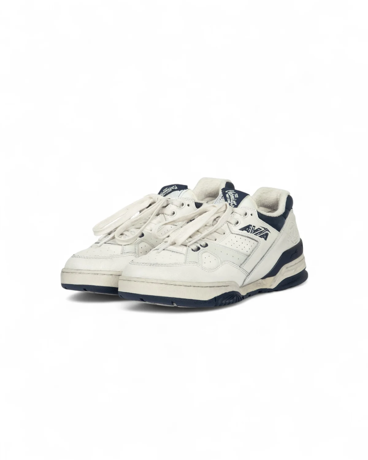 Pair of Chemist Creations AVIA 855 sneakers in cream leather with navy accents, oversized laces, perforated panels, and retro running sole inspired by the Chemist’s® Thrift Store concept