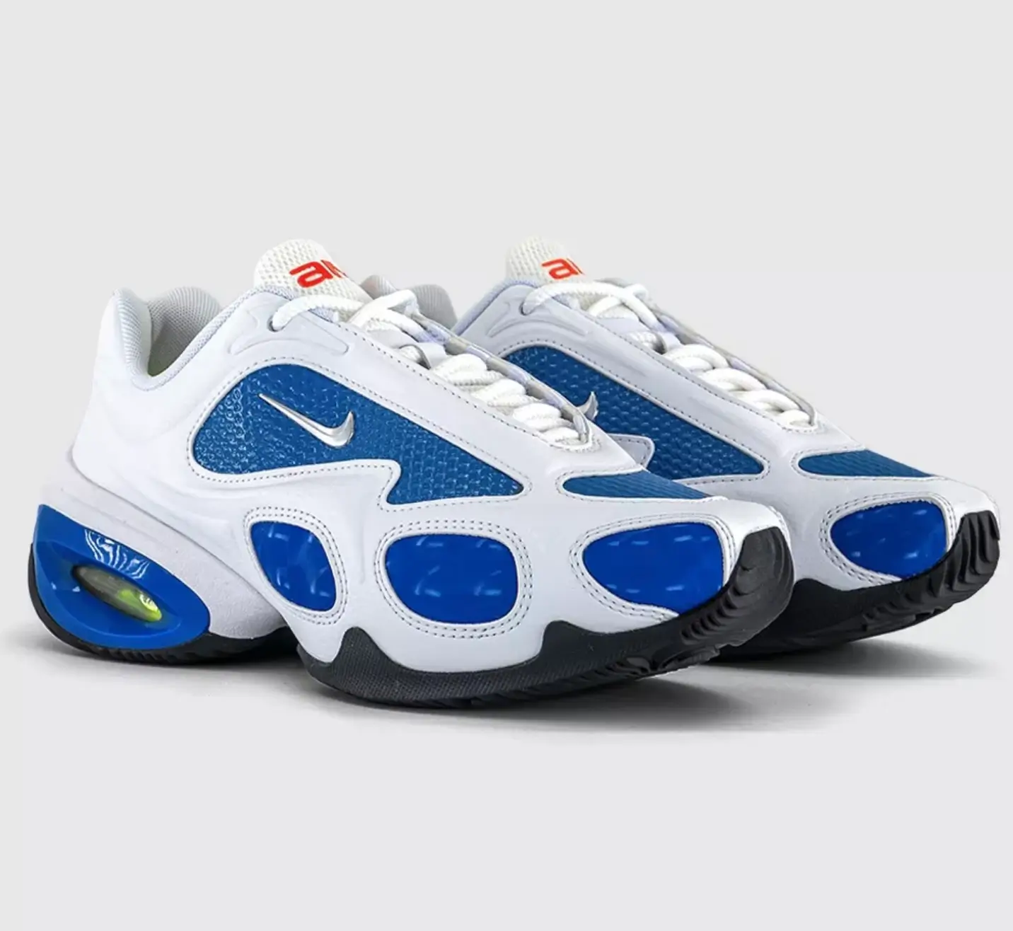Pair of Veneda Carter x Nike Air Max Muse trainers in white and racer blue, featuring metallic silver Swooshes, sculpted white leather overlays, blue mesh panels, and a visible Air unit with volt cushioning on the heel