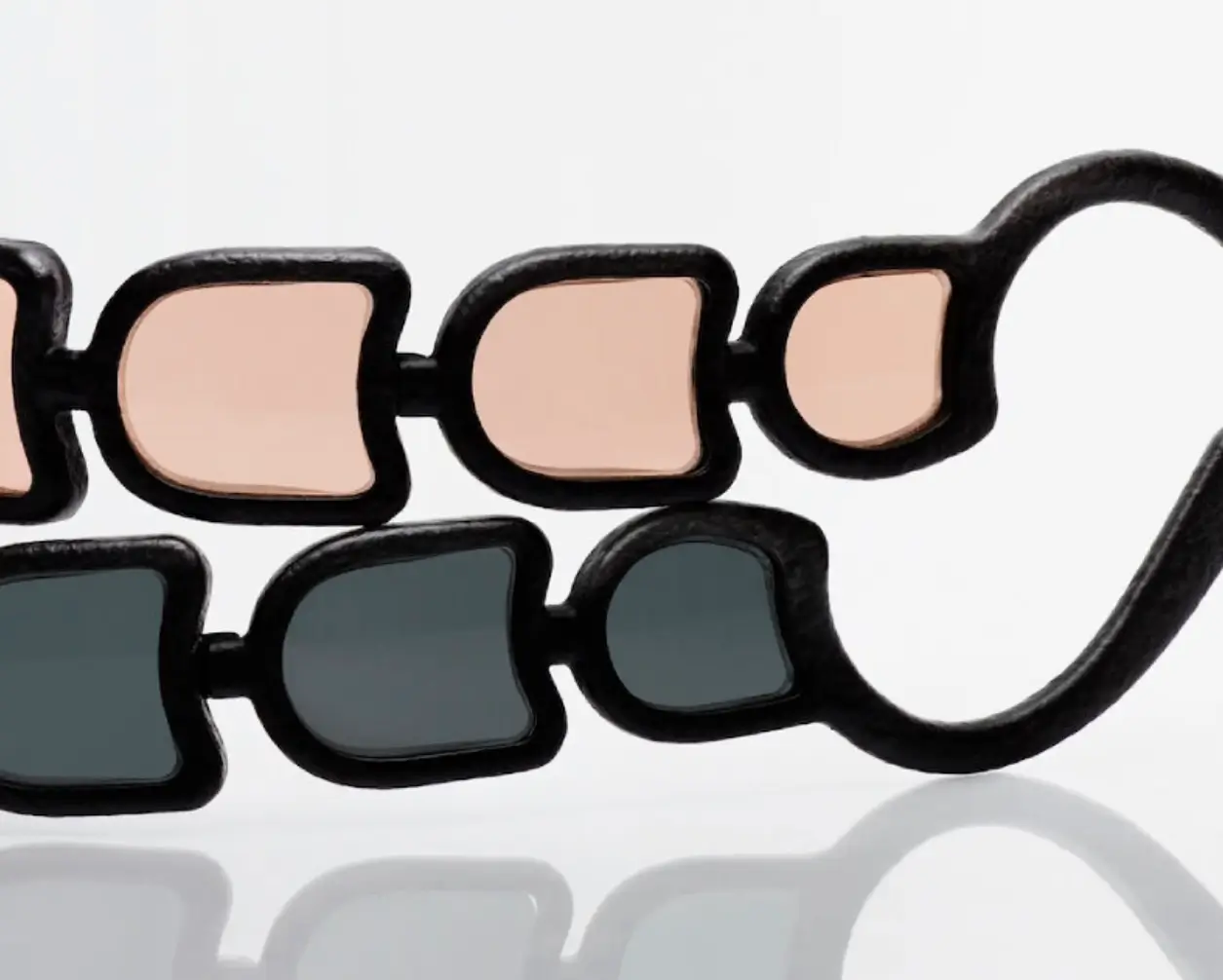 Close-up of Issey Miyake Eyes UROKO sunglasses showing multiple concave lenses arranged in a repeating row within a sculptural black frame, highlighting the segmented optical design inspired by Shoji Kamoda’s ceramic patterns