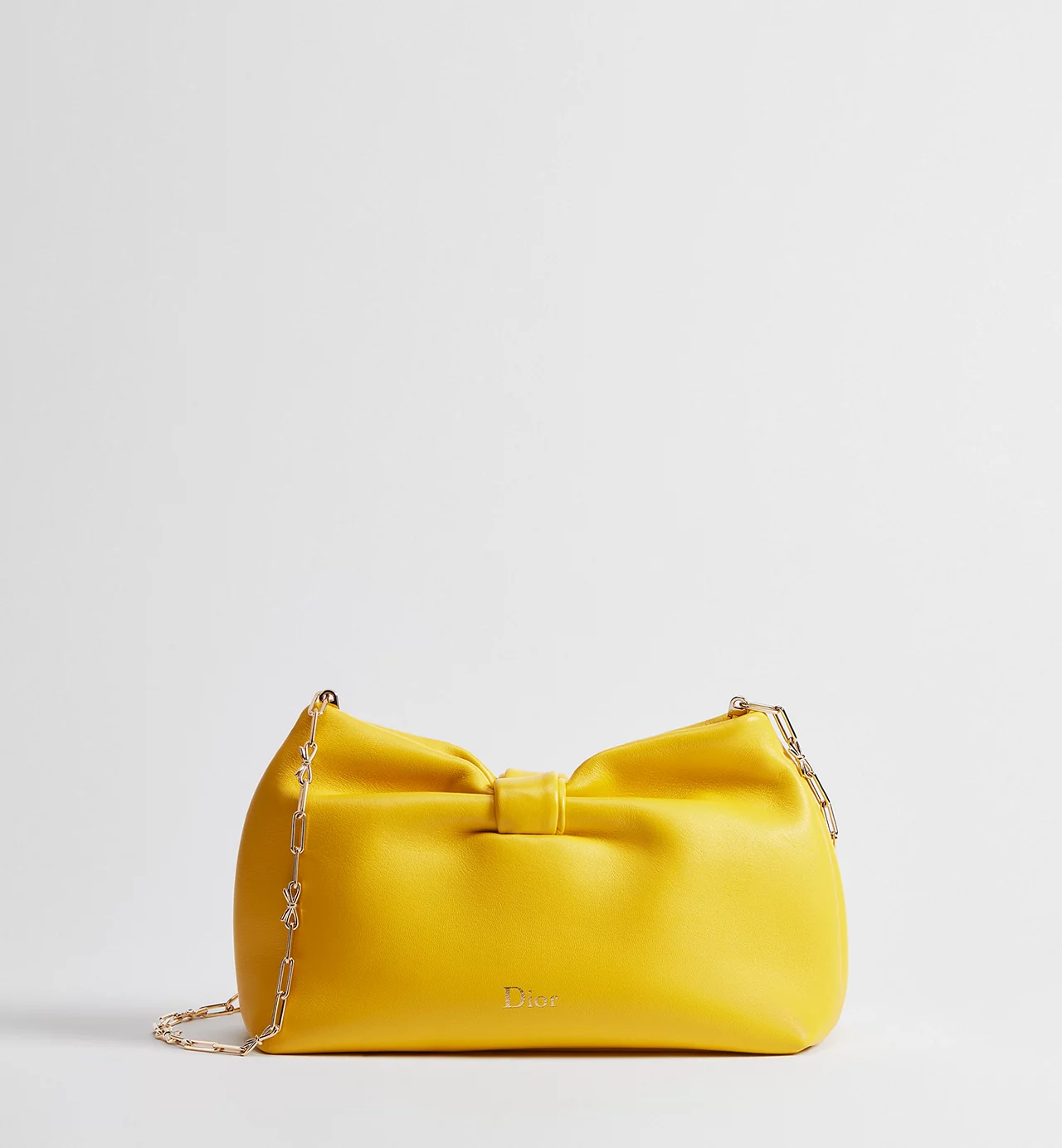 Small Dior Bow Bag in buttercup yellow lambskin displayed with gold-tone chain strap draped along the side, featuring a soft sculptural bow detail and subtle Dior logo on the front