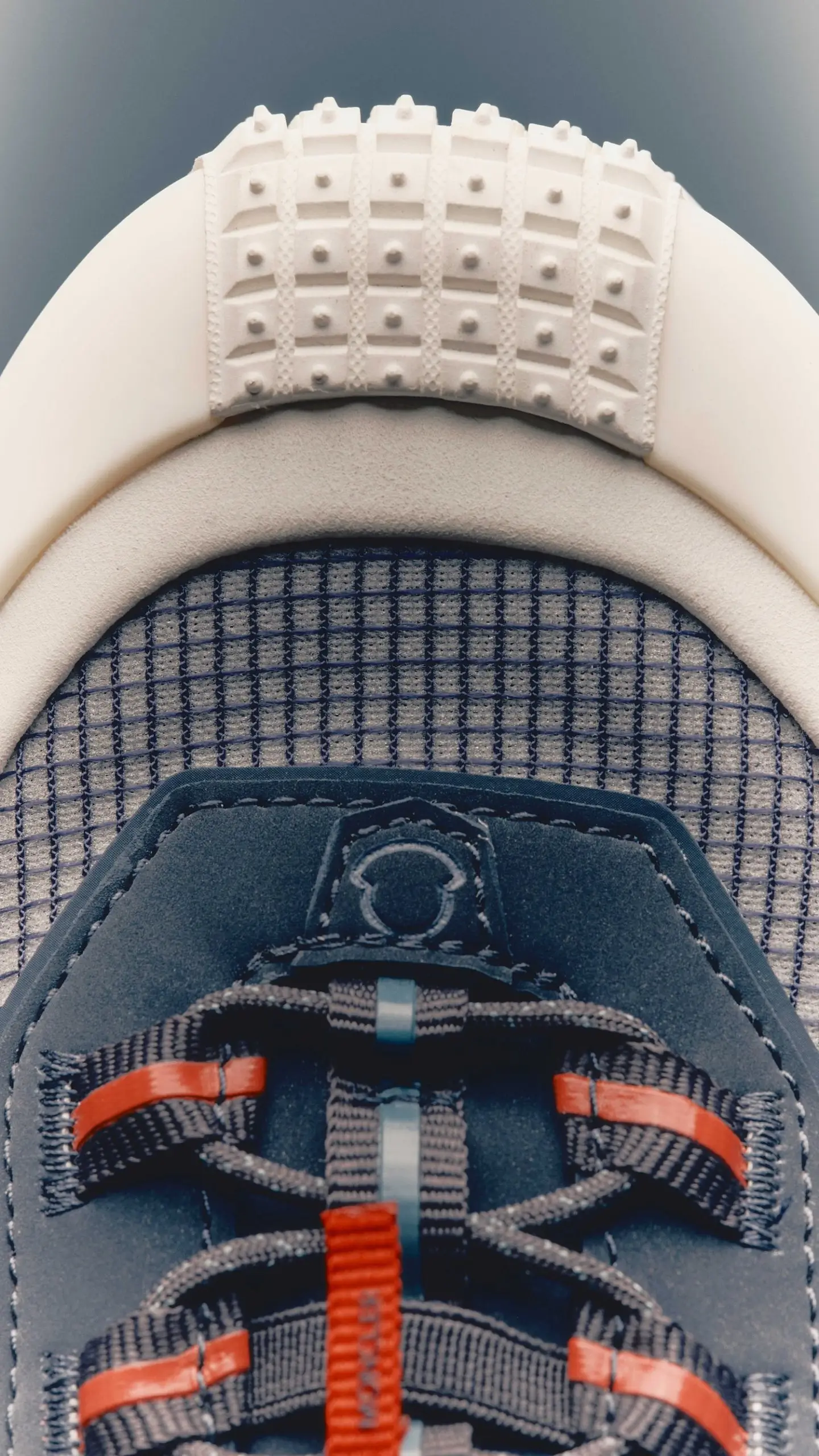 Top-down close-up of Moncler Trailgrip LP sneaker showing textured mesh upper, suede panel with embossed logo, and technical lacing system with red and blue webbing accents