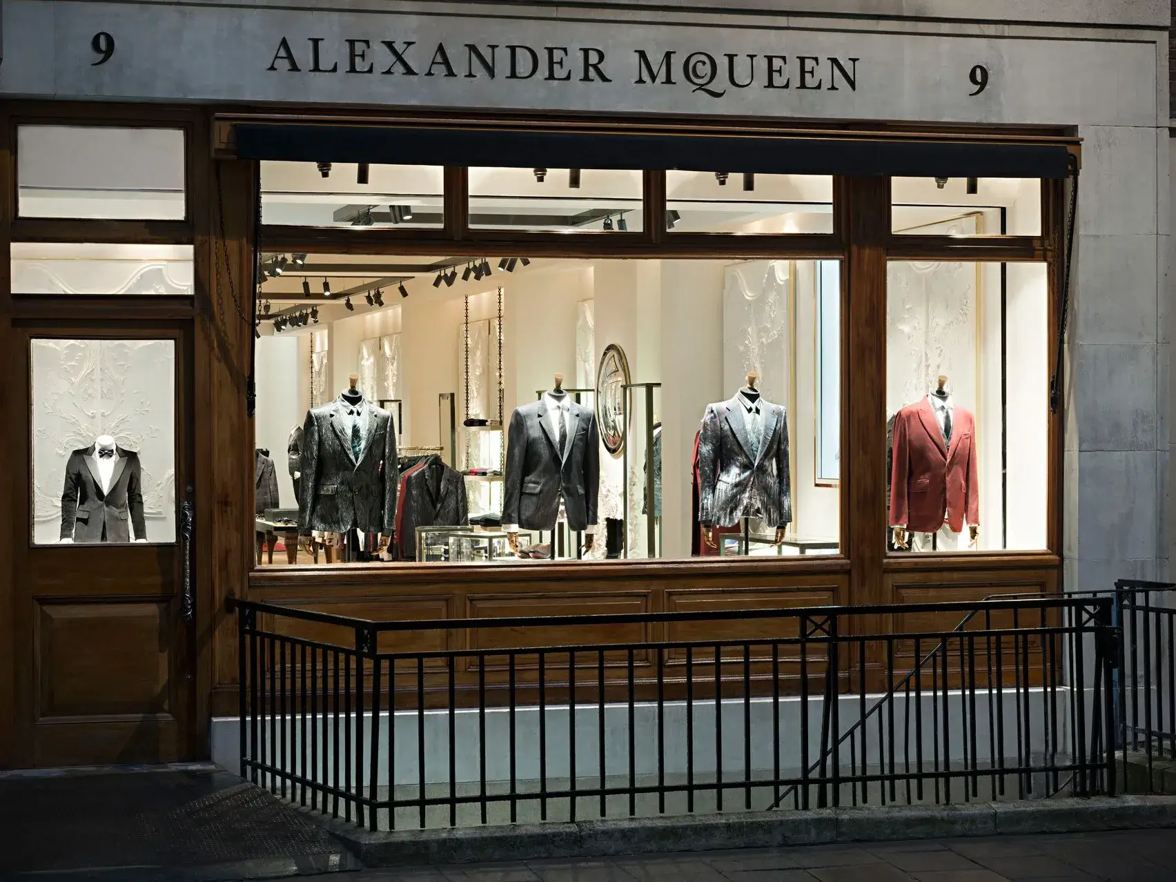 Alexander McQueen retail store facade with mannequins dressed in tailored suits and formalwear visible through the display windows