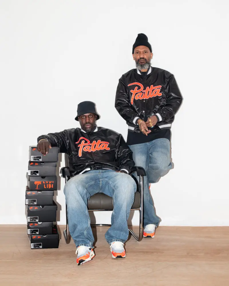 Edson Sabajo and Guillaume Schmidt pose wearing Patta varsity jackets and Nike Air Max 1 “Wave” sneakers beside stacked Patta x Nike shoe boxes during the campaign celebrating the collabs fifth anniversary