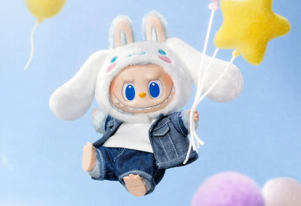 Labubu designer toy wearing a fluffy white bunny hood inspired by Sanrio’s Cinnamoroll, dressed in a denim outfit and floating with star-shaped balloons against a soft blue background