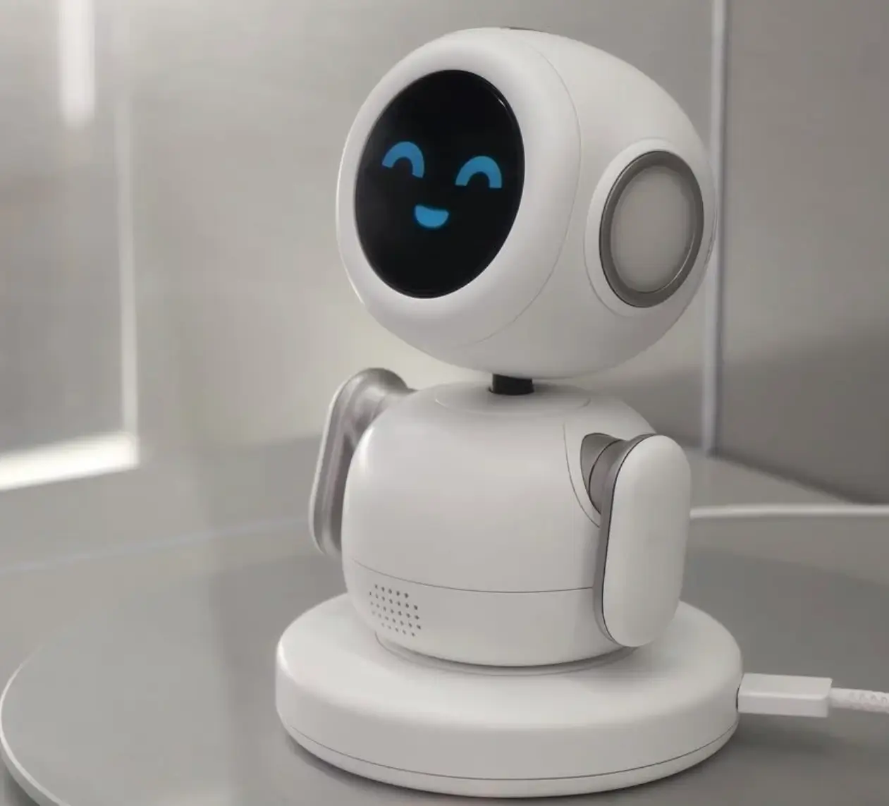 Samsung Mini PetBot AI companion robot with animated OLED face smiling while sitting on a charging base on a desk