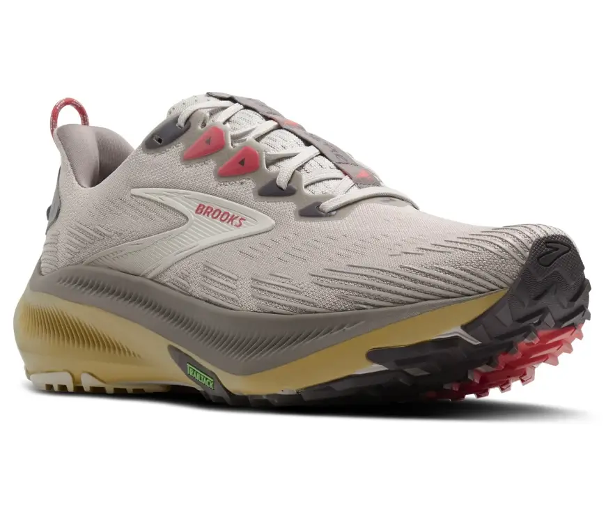Angled view of the Staple x Brooks Running Ghost Trail sneaker featuring a breathable grey mesh upper, pink eyelet accents, cushioned midsole, and rugged trail outsole with red traction lugs
