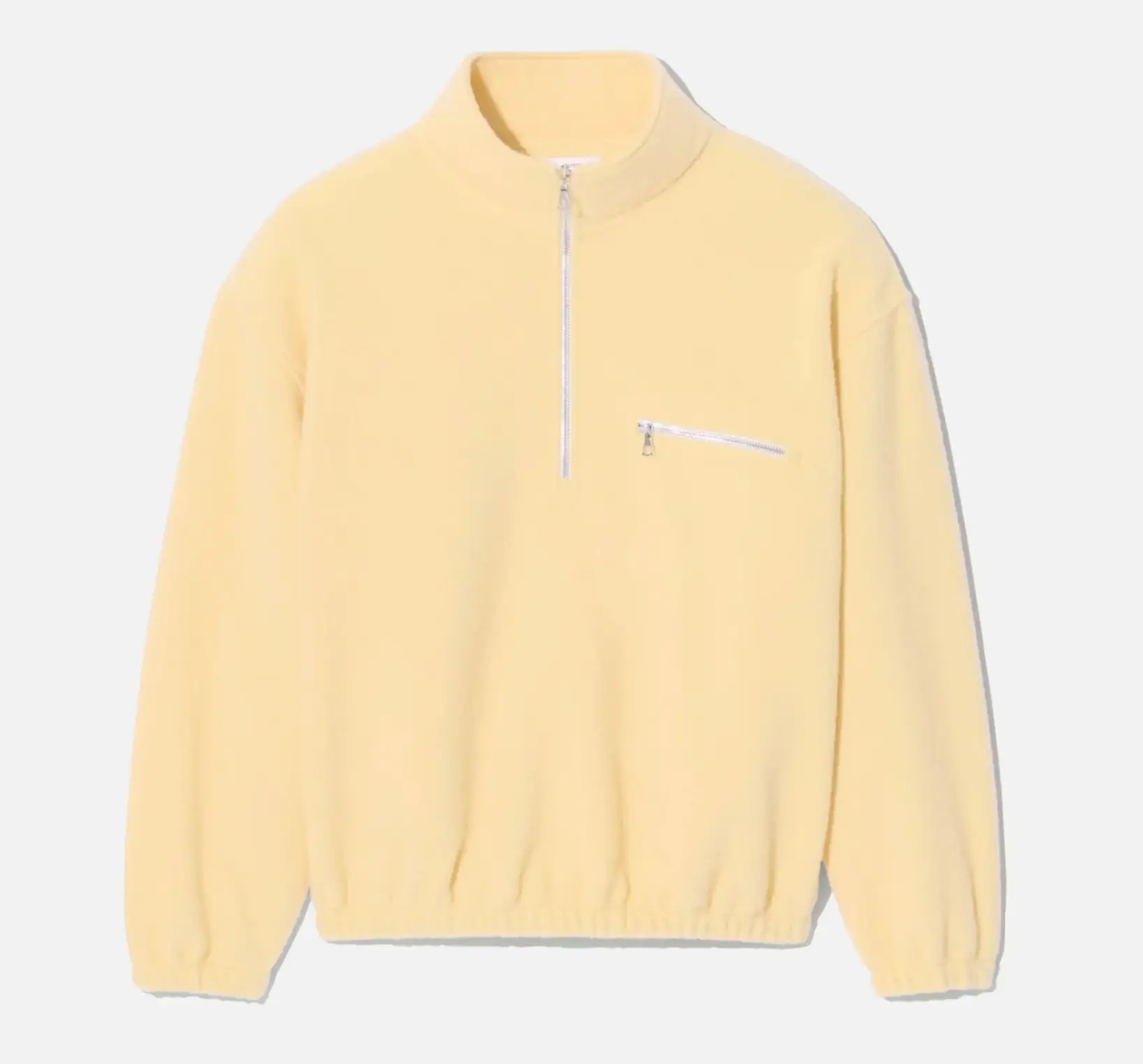 Rier natural wool fleece jacket in soft pale yellow featuring a half-zip front with Riri metal zipper, standing collar, chest pocket with zip closure, and elasticated cuffs and hem in a clean minimalist silhouette