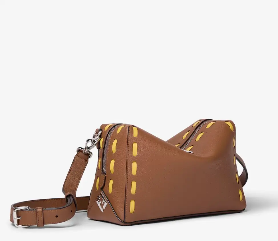 Side view of Fendi Liu duffle bag in tan granulated leather with yellow whipstitch detailing, FF hardware, and adjustable strap