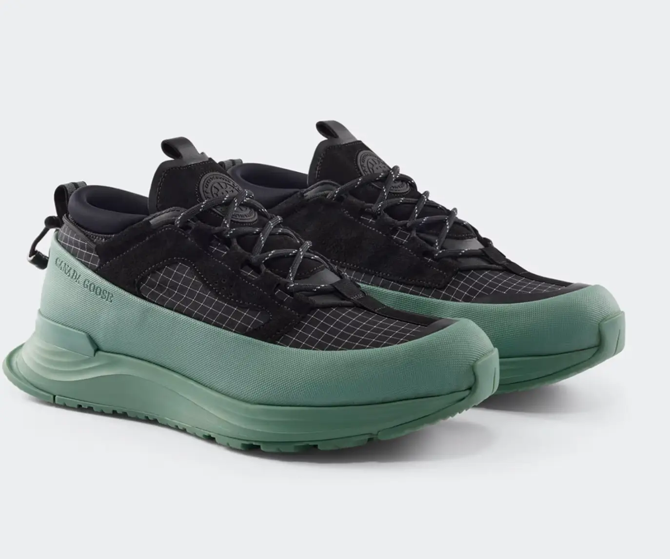 Women’s Glacier Trail Sneaker in Dyneema® featuring a black ripstop upper with visible grid texture, reinforced lace system, and a sculpted sage-green midsole with extended rubberized rand, shown in a low-profile alpine-inspired silhouette designed for lightweight durability and multi-terrain traction
