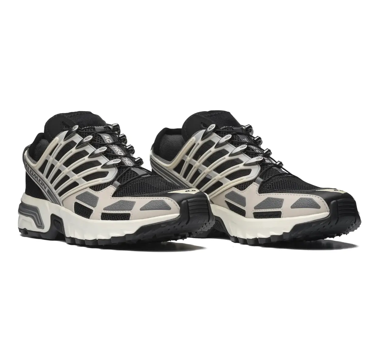 Pair of Salomon ACS Pro Shell sneakers in Rainy Day/Black/Castlerock shown in studio, featuring breathable black mesh uppers, off-white skeletal cage overlays with cut-out ventilation, Quicklace system, and rugged Contagrip outsole