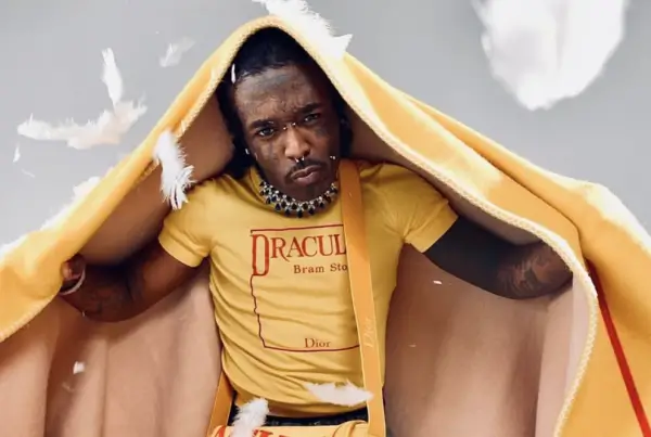 Lil Uzi Vert poses in a yellow Dior outfit featuring a “Dracula” graphic top, partially draped in a matching hooded layer, blending gothic literary reference with high-fashion styling