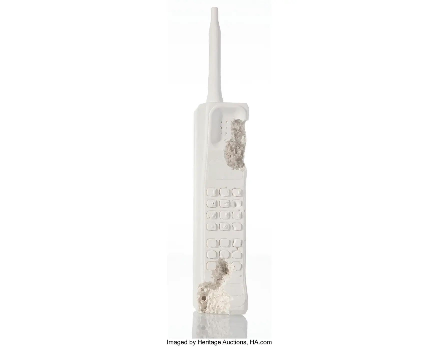 Daniel Arsham Mobile Phone (FR 01) (2013) sculpture in white plaster with embedded glass fragments, depicting an eroded vintage mobile phone with antenna and keypad, partially crystallized along the side and base against a minimal white background
