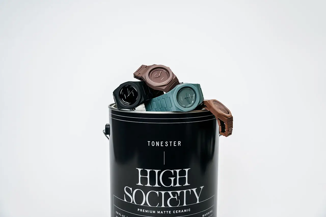 Tonester “High Society” Milano matte ceramic watches in muted tones—black, teal, rose, and brown—stacked atop a black cylindrical display container