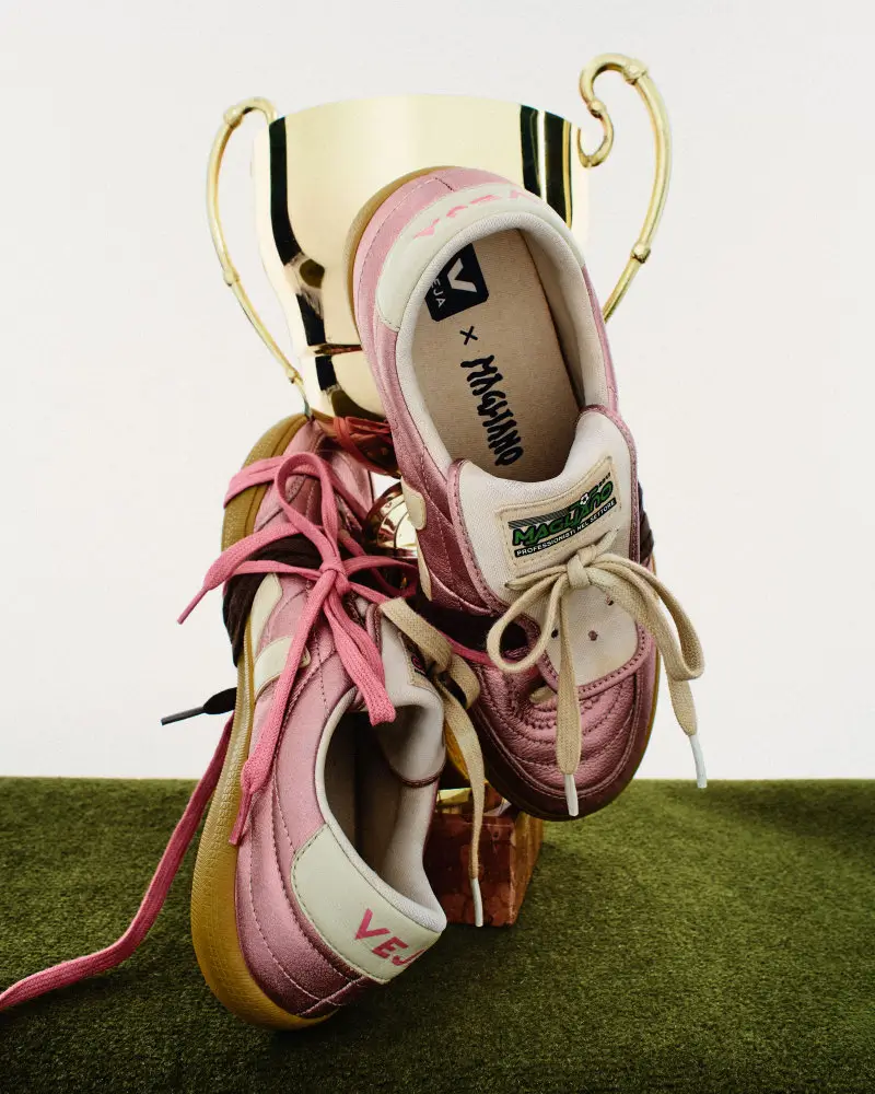 Magliano x VEJA Panenka shoes in pearlescent pink displayed beside a gold trophy, highlighting the football-inspired design and fold-over tongue