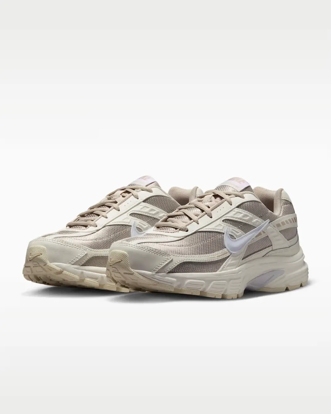Pair of Nike Initiator sneakers in “Sail Cream” colorway, shown in a three-quarter front angle. The shoes feature breathable beige mesh uppers with layered cream synthetic overlays, a glossy white Swoosh, tonal laces, and a cushioned off-white midsole with subtle gum accents on the outsole