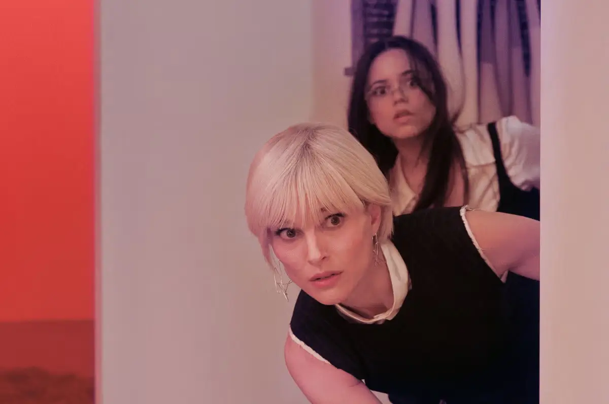 Natalie Portman standing inside a contemporary art gallery in a scene from The Gallerist, surrounded by minimalist white walls and modern artworks during a tense exhibition moment