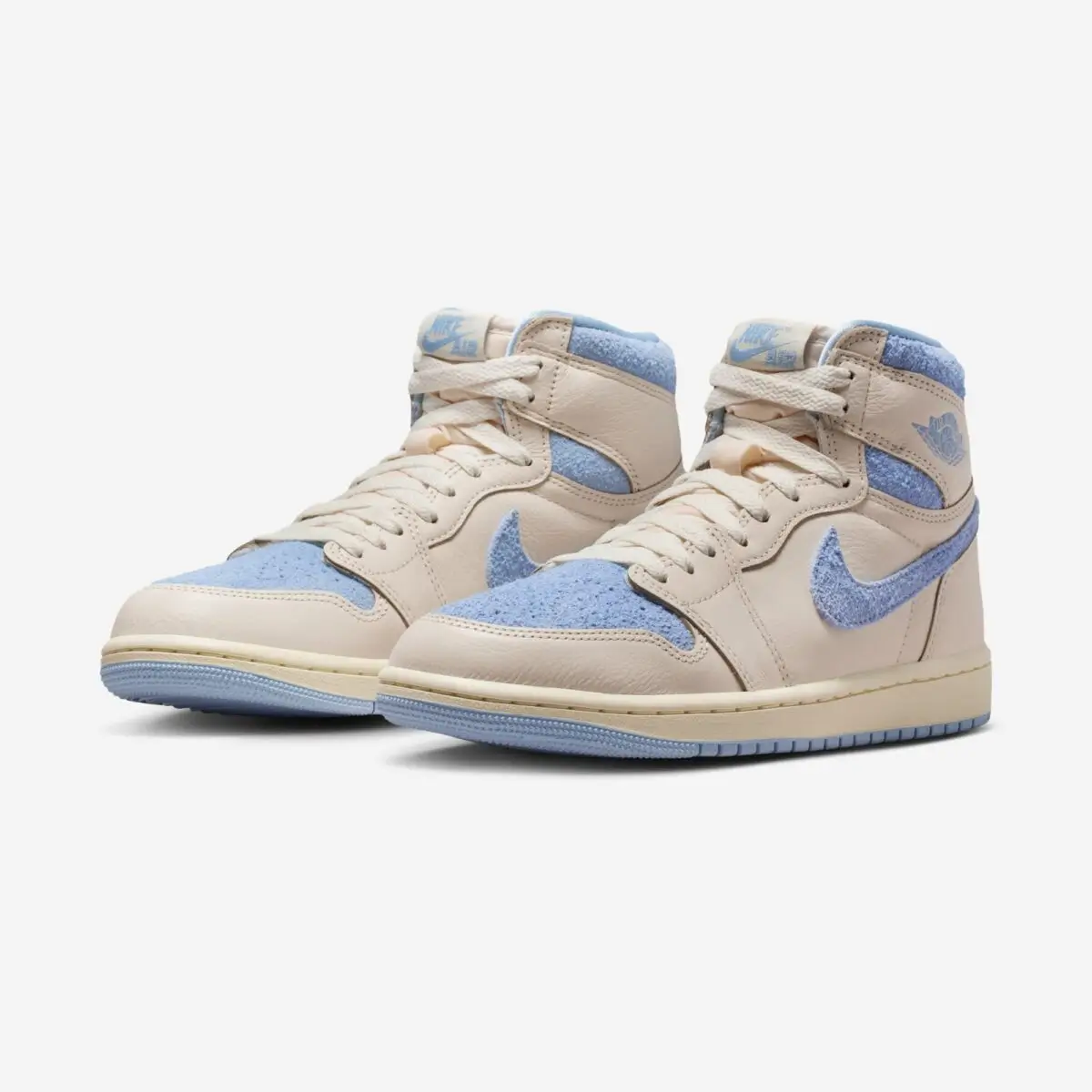 Pair of Air Jordan 1 High OG WMNS “Psychic Blue” sneakers featuring cream leather uppers, textured pastel blue Swooshes and toe boxes, and light blue rubber outsoles
